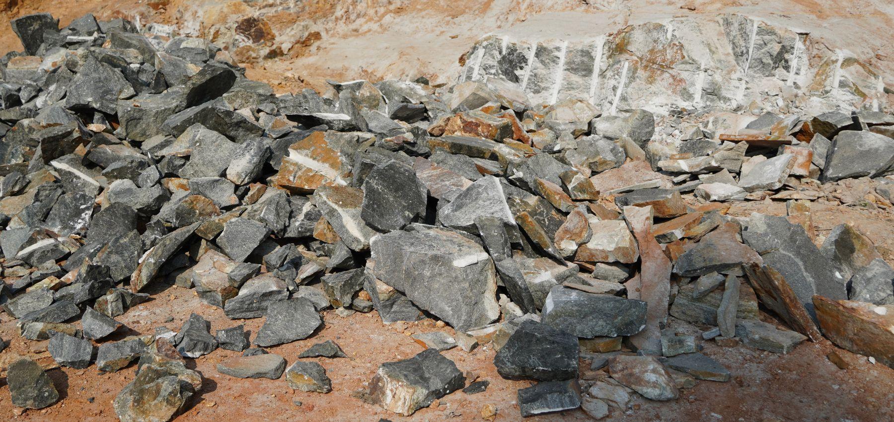 A pile of grey and brown coloured zeolite rocks on the ground after excavation