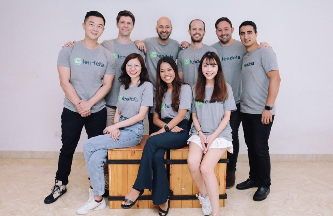 Six men standing behind three women sitting down all wearing matching corporate t-shirts.